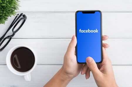 KHARKOV, UKRAINE - December 23,2018: Woman holding iPhone with Facebook social network application on screenのeditorial素材