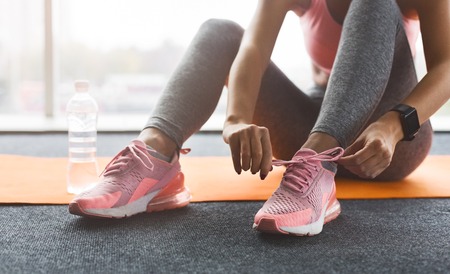 Woman tying laces preparing for training, wearing sneakers, crop, closeupの写真素材