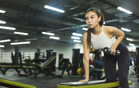 Slim girl warming up with weights in health club, copy spaceの写真素材