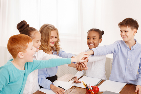 School children putting their hands together in classroomの写真素材
