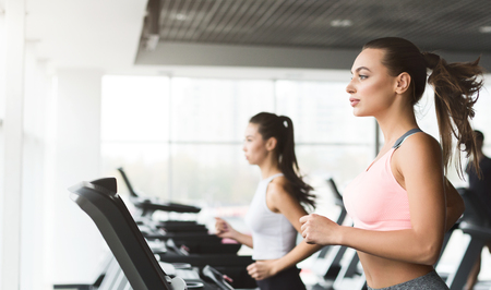 Sports women exercising on running track in gym, side view, copy space