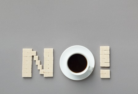 Sweet refuse. Sugar cubes and cup of coffee arranged as word NO on gray background, top view, copy spaceの写真素材
