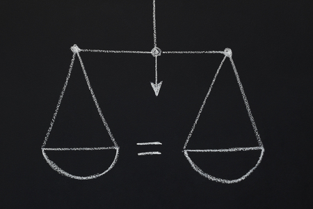 Drawn scales with equal scalepans on black chalkboard. Symbol of balance, choice, uncertainty, justice, decision makingの写真素材