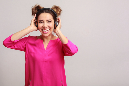 Joyful woman with headphones listening to music, grey background, copy spaceの写真素材