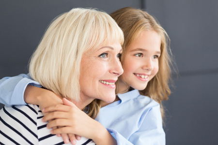 Senior woman and little girl spending time together, looking asideの写真素材