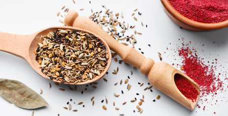 Mixed spices in wooden spoon and sumac in scoop on white backgroundの写真素材