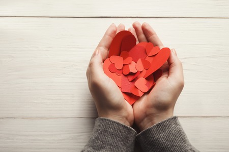 Valentine background with diy handmade paper hearts in womans hands at rustic white wood planks. Happy lovers day card mockup, copy spaceの写真素材
