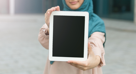 Muslim woman holding tablet in front of face. Technology for life concept, copy spaceの写真素材