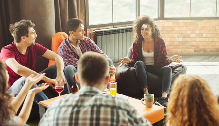 Friends having fun at home party. Guess who I am conceptの写真素材