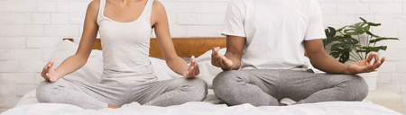 Mental unity. Unrecognizable black couple meditating together, sitting in lotus position in bed, panoramaの写真素材