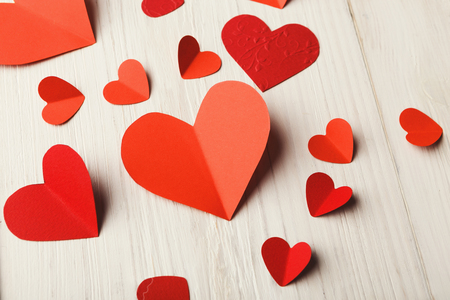 Valentine background with handmade paper hearts on white rustic wood. Happy lovers day card mockup, copy spaceの写真素材
