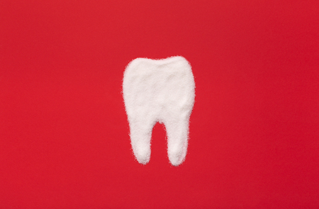 White tooth made from sugar sand on red background, top viewの写真素材