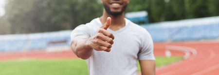 Black athlete man with thumbs up gesture on stadium background. Everyday outdoor workout conceptの写真素材