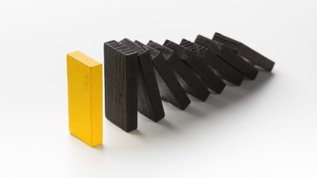 Risk business strategy. One yellow block stop falling black ones on white backgroundの写真素材