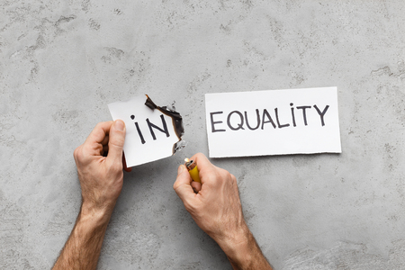 Equality concept. Man burning word In as part of Inequality, gray backgroundの写真素材