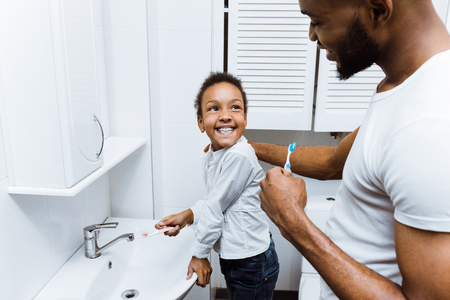 African-american girl brushing teeth with dad in bathroomの写真素材