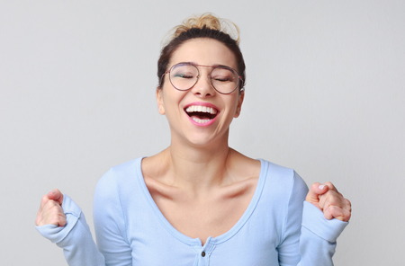 Happy young woman posing and shouting over grey