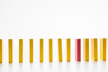 Corporate espionage. One red wooden block among yellow ones, white studio