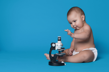 Adorable baby boy sitting with microscope on blue studio background, panorama, copy spaceの写真素材