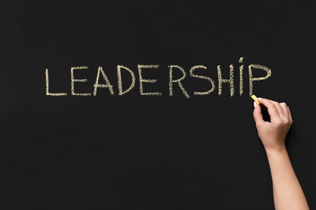 Woman writing word Leadership with yellow chalk on blackboard, copy spaceの写真素材