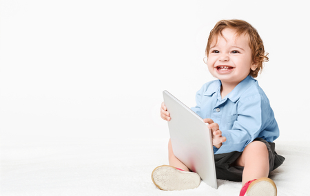 Laughing cute baby playing with digital tablet, took forbidden thing, copy space, panoramaの写真素材