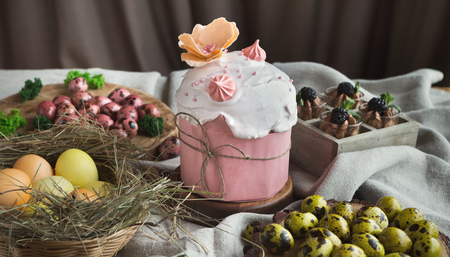 Traditional Easter sweet cake decorated with pink meringue and various coloured eggs on light...
