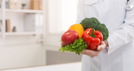 Diet and Healthy concept. Nutritionist holding bunch of fresh vegetbles in her office, panorama with copy spaceの写真素材