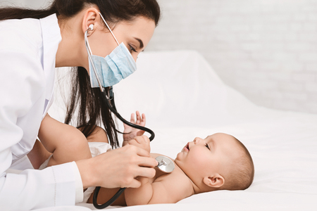 Baby is sick. Pediatrician listening to child breath, examining lungs with stethoscope, free spaceの写真素材