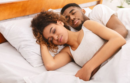 Lovely sleep position. African-american couple sleeping in bed and hugging, free spaceの写真素材