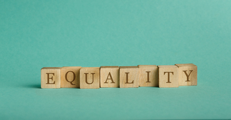 Vintage alphabet blocks spelling out the word equality, turquoise panorama background