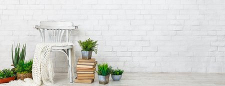Cozy corner. Chair and plants on books over white brick wall, blank spaceの写真素材