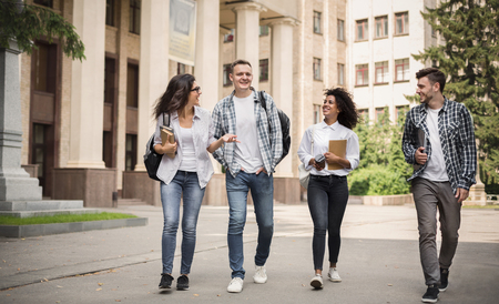 Multiethnic group of smiling students walking together on university backgroundの写真素材