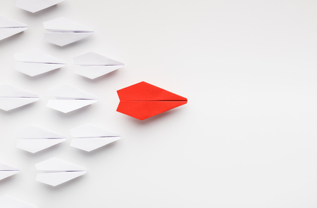 Opinion leadership concept. Red paper plane leading another ones, influencing the crowd, white background, top view with free spaceの写真素材
