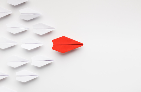 Opinion leadership concept. Red paper plane leading another ones, influencing the crowd, white background, top view with free space