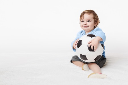 Cute little boy holding football and looking at copy space, white studio background, panoramaの写真素材