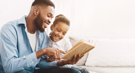 African-american dad and daughter reading book together at home, copy spaceの写真素材