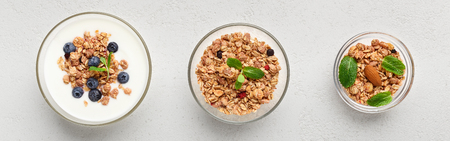 Granola, yogurt, blueberries in bowls on grey background, top view. Low cal breakfast concept
