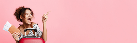 African-american woman with tickets pointing finger away over pink background, empty spaceの写真素材