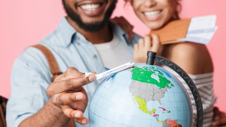 Happy couple planning and preparing for journey, choosing route, pink background, cropの写真素材