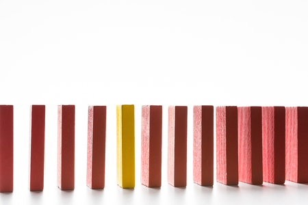Think different concept. One yellow wooden block standing between red ones, white background, free spaceの写真素材