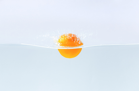 Detox. Fresh orangefruit falling in water with splash, blue background, free spaceの写真素材