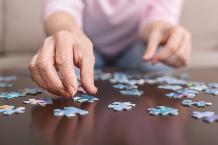 Memory training. Senior woman playing puzzle at home, closeupの写真素材