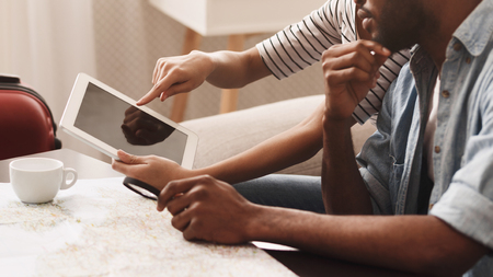 Young couple booking hotel online on tablet, preparing for trip