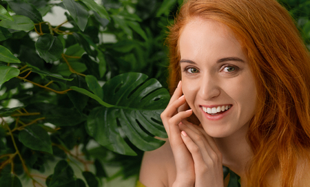 Cheerful redhead woman laughing on green leaves background, free spaceの写真素材