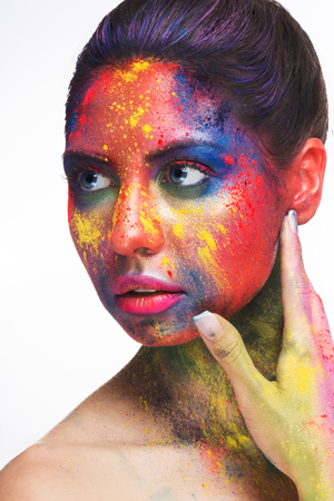 Holi colors festival. Young woman with colorful powder art make-up on white studio background, closeup portraitの写真素材