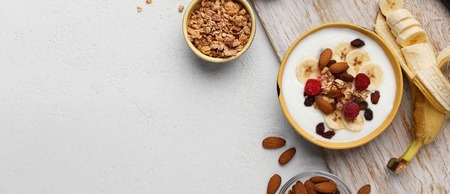 Bowls with yogurt, granola and almond on white background, top view, copy space. Homemade breakfast conceptの写真素材