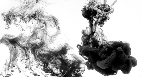 Black dye swirling in water on white backgroundの写真素材