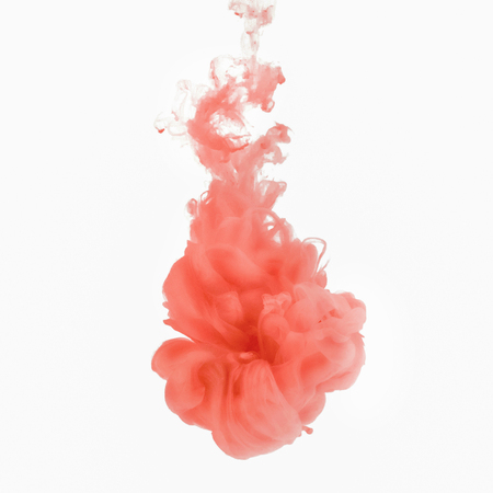 Pink smoke swirling underwater on white background.の写真素材