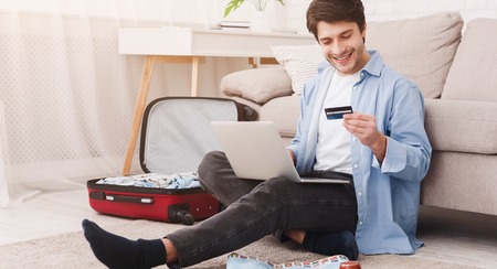Travelling alone. Man preparing for vacation, booking tickets online at homeの写真素材