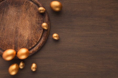 Background with golden decorated easter eggs on wooden background, copy spaceの写真素材